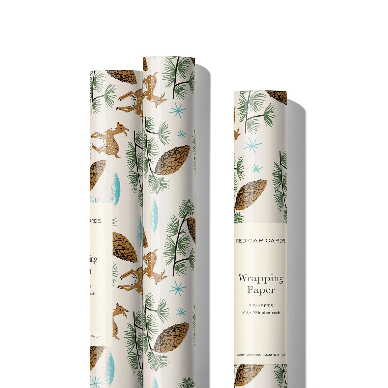 3 rolls of white wrapping paper with images of deer and pine cones on them on a white background.