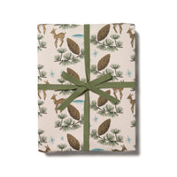 Gift box with images of deer and pine cones and green ribbon on a white background.