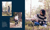 Woman and her dog wearing matching sweaters in a forest setting