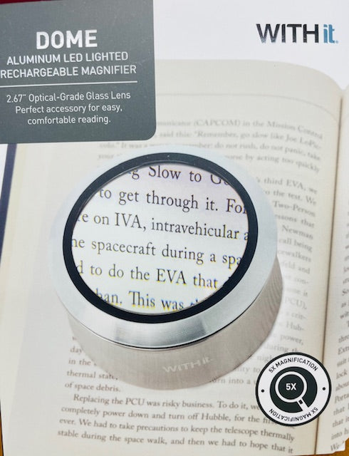 Dome aluminum LED lighted rechargeable magnifier on an open book with 'WITHit' branding.
