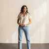 A woman wearing a white collard shirt and blue jeans.