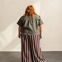 A woman with her back turned wearing a grey shirt.