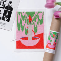 Needlepoint canvas with hite candle in a pink bowl on a pink, red, and green background