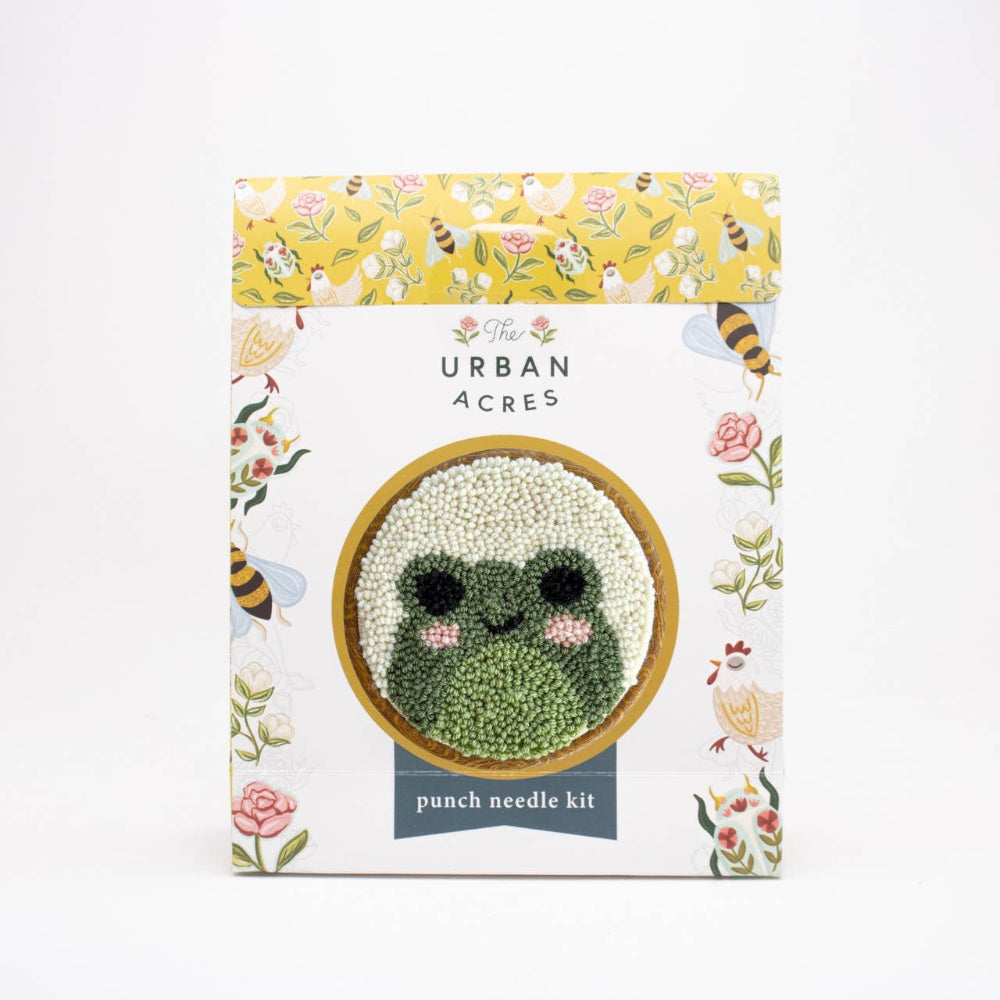 Punch needle kit packaging with a green knitted frog design on a white background.