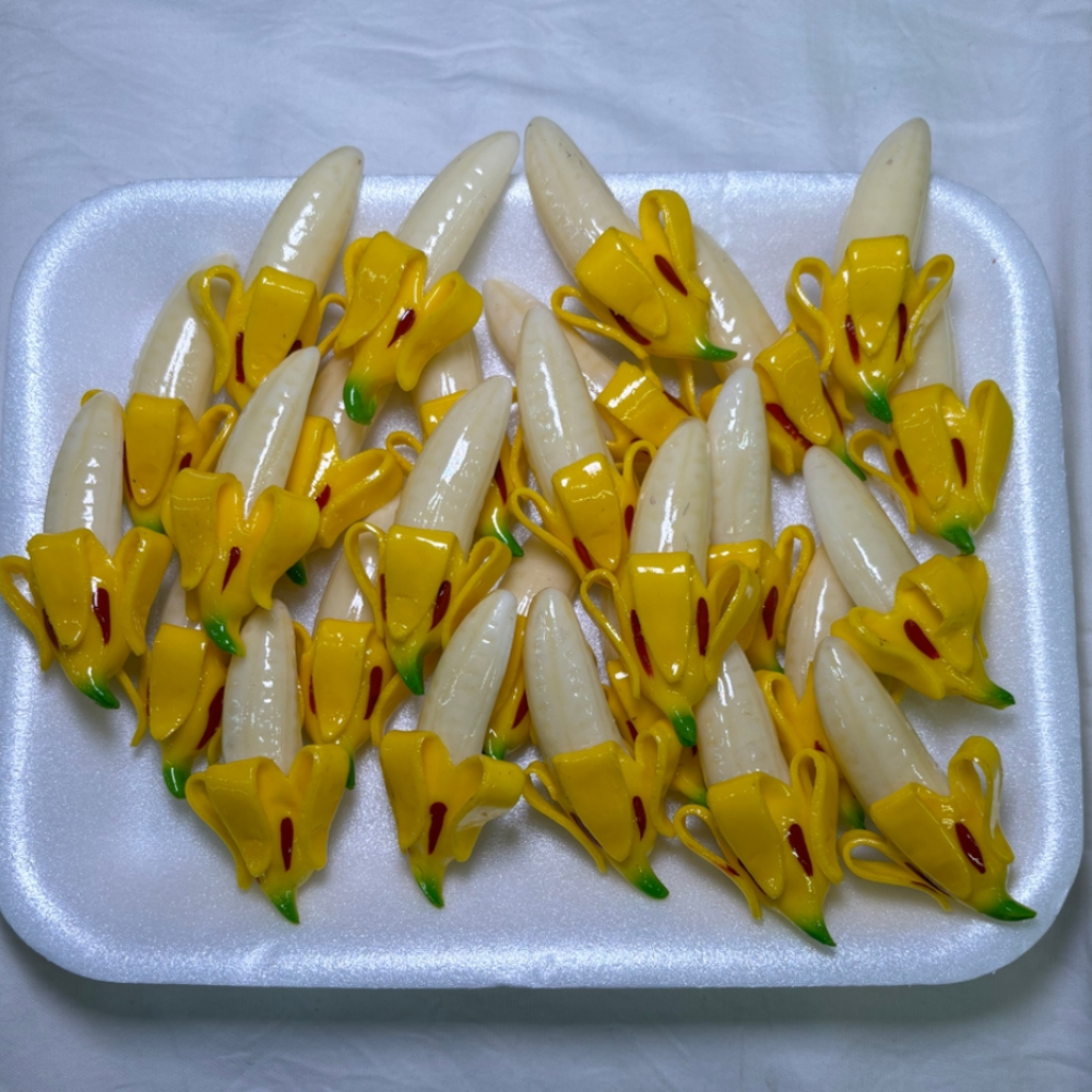 white tray of white and yellow banana magnets. Each magnet's banana is half peeled.