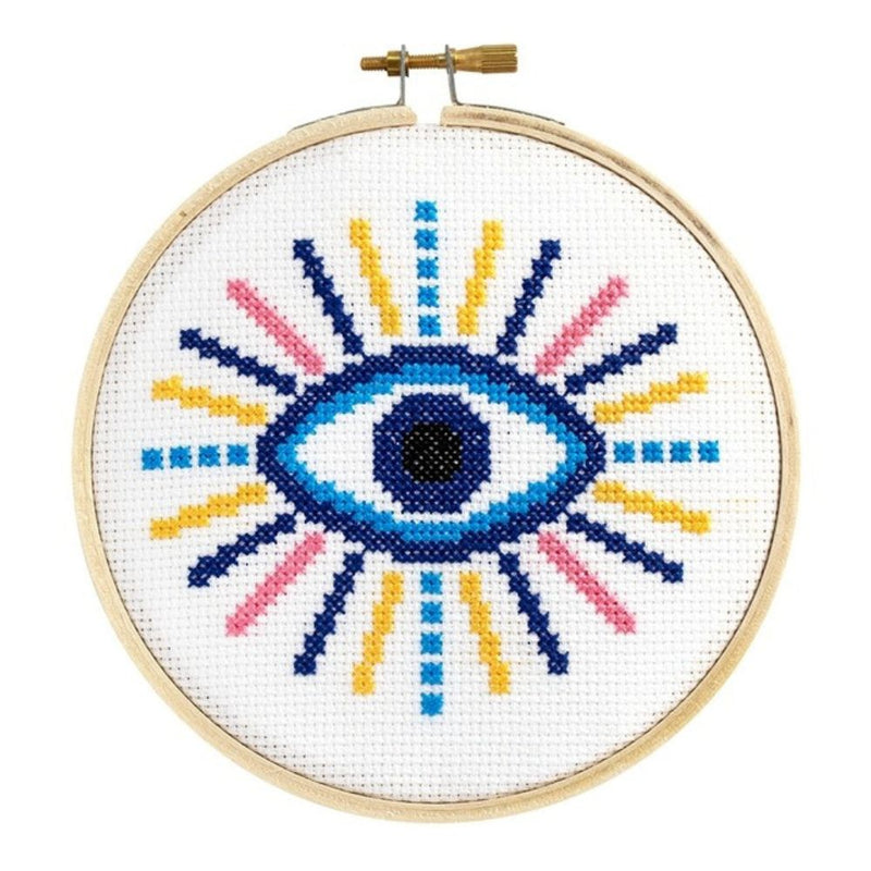 Cross-stitched eye design in a wooden hoop on a white background