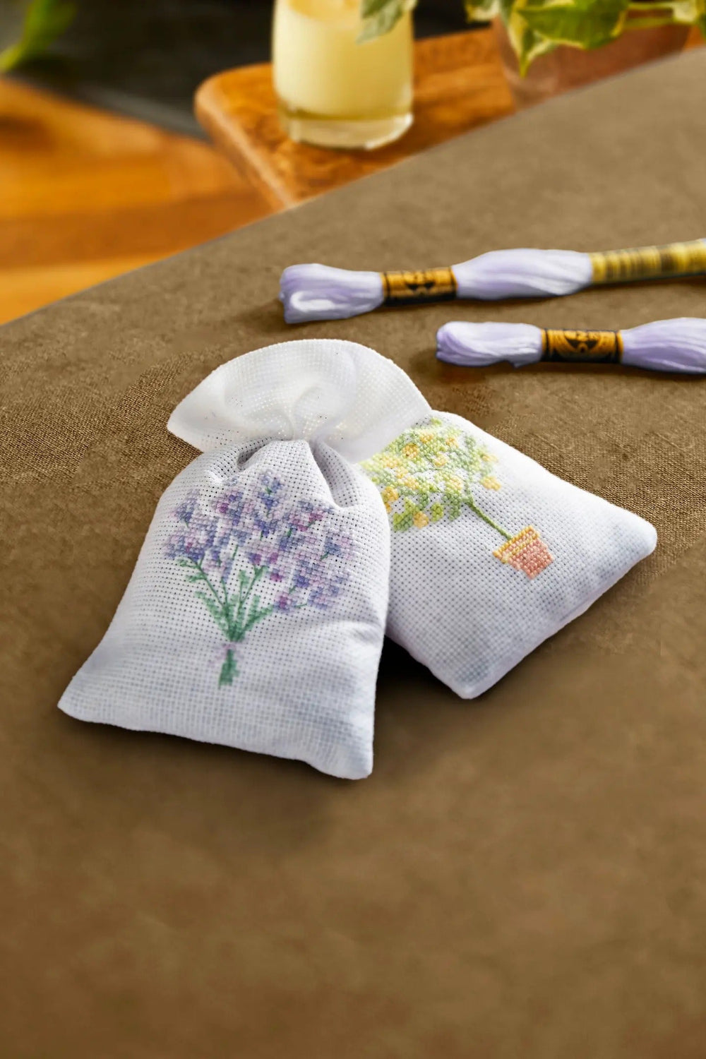Two embroidered sachets with floral designs on a wooden surface.