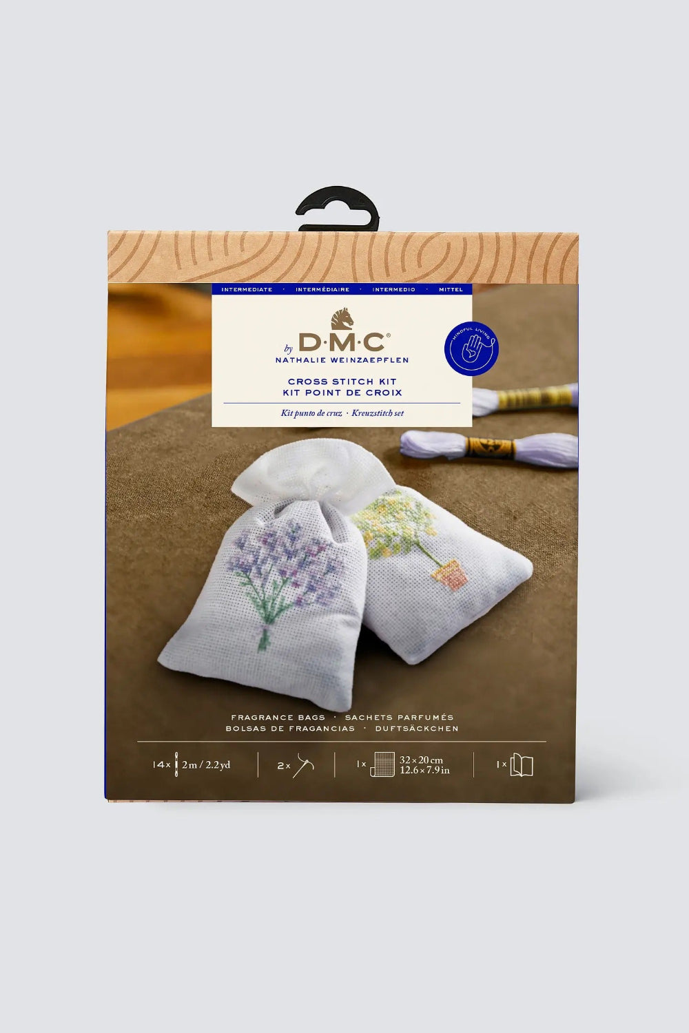 DMC cross stitch kit packaging with two embroidered bags on a wooden surface.