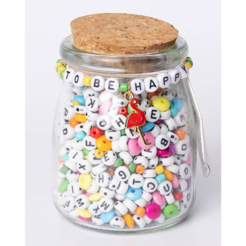 Glass jar with cork lid containing letter beads and round rainbow beads. Letter beads on top read "to be happy."