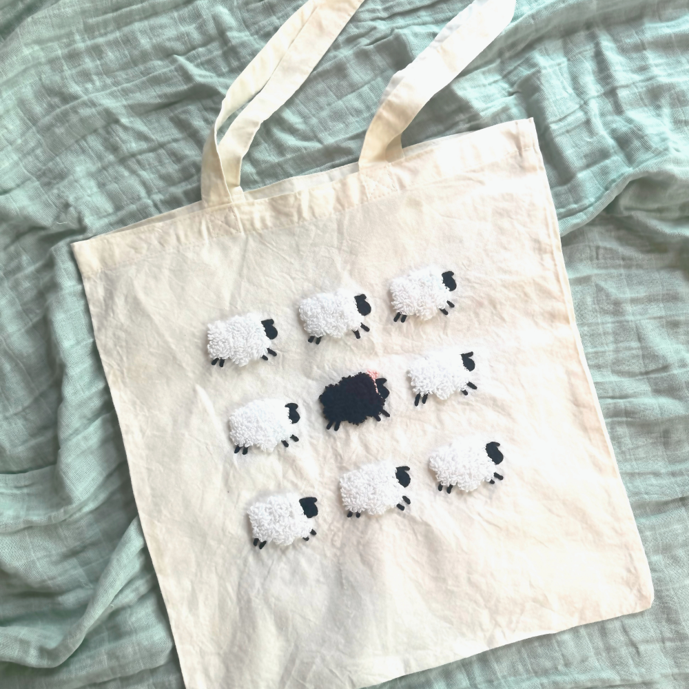 Tote bag with punch needled sheep design on a textured surface