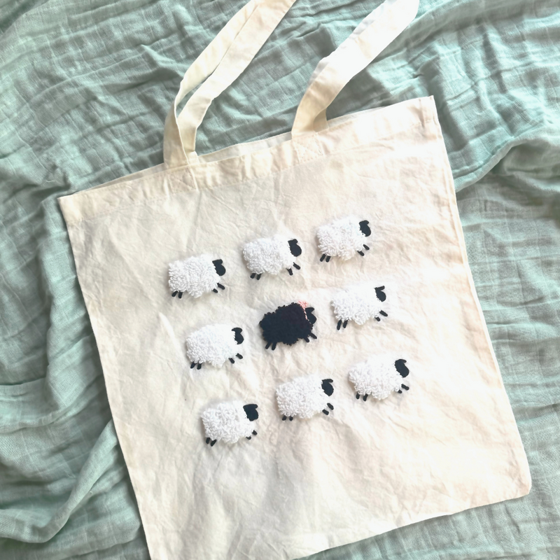Tote bag with punch needled sheep design on a textured surface