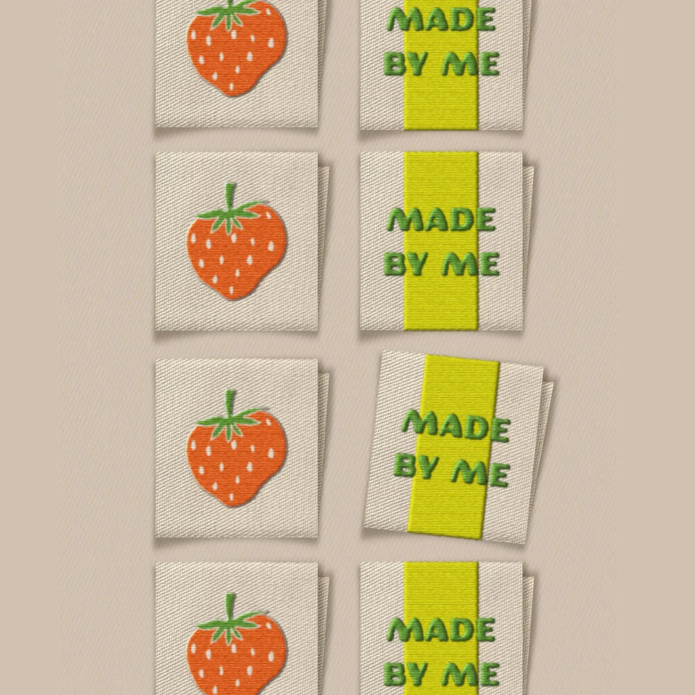 Embroidered labels with strawberry design and 'Made by Me' text on a beige background