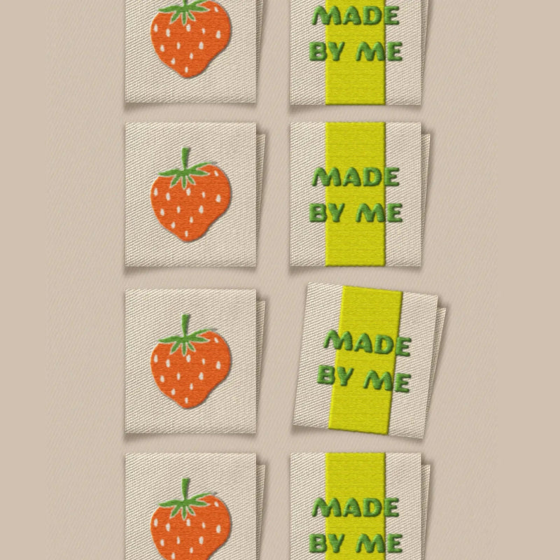 Embroidered labels with strawberry design and 'Made by Me' text on a beige background