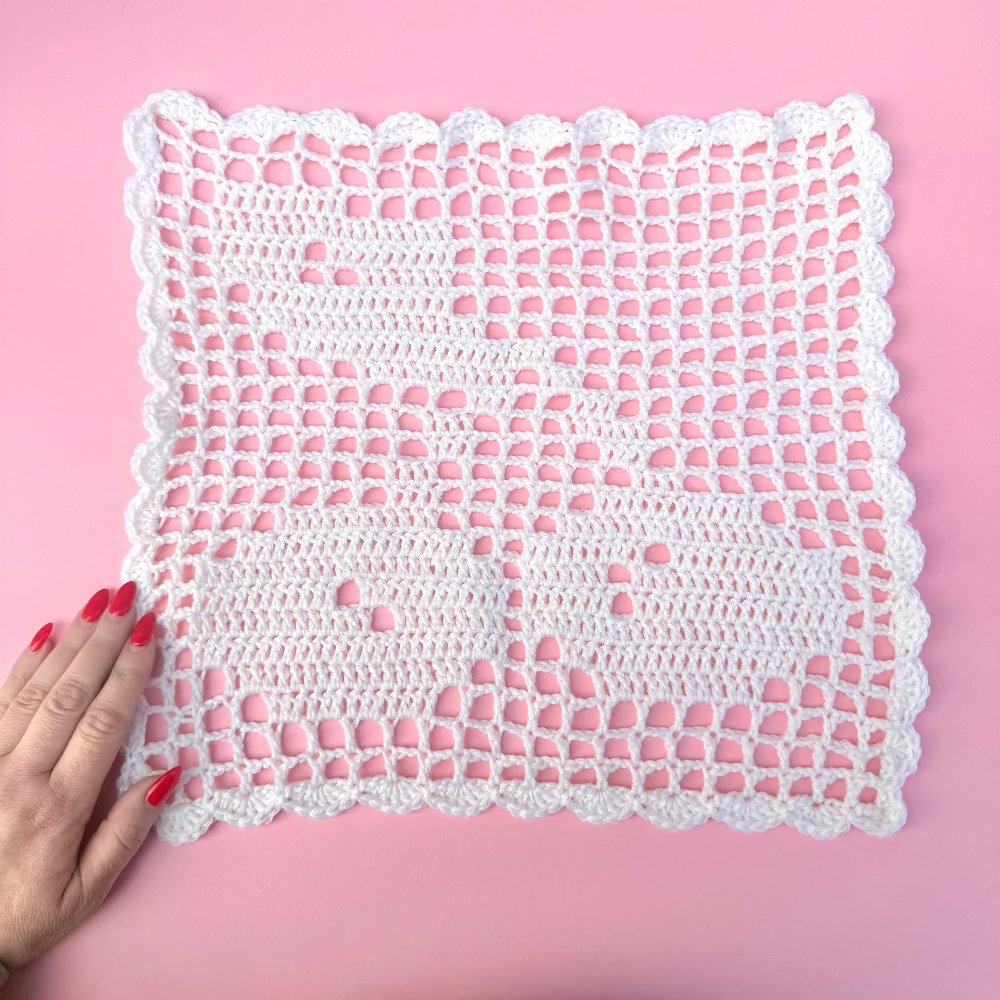 filet crochet cherry design on a pink background 