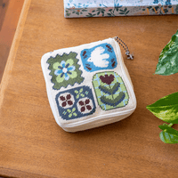 A square zippered pouch with a classic needlepoint design featuring a dove and flowers