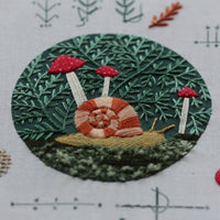Embroidery stitch sampler with snail and mushrooms