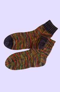 Multicolored socks, one with a dark gray toe, heel, and cuff, on a light gray background