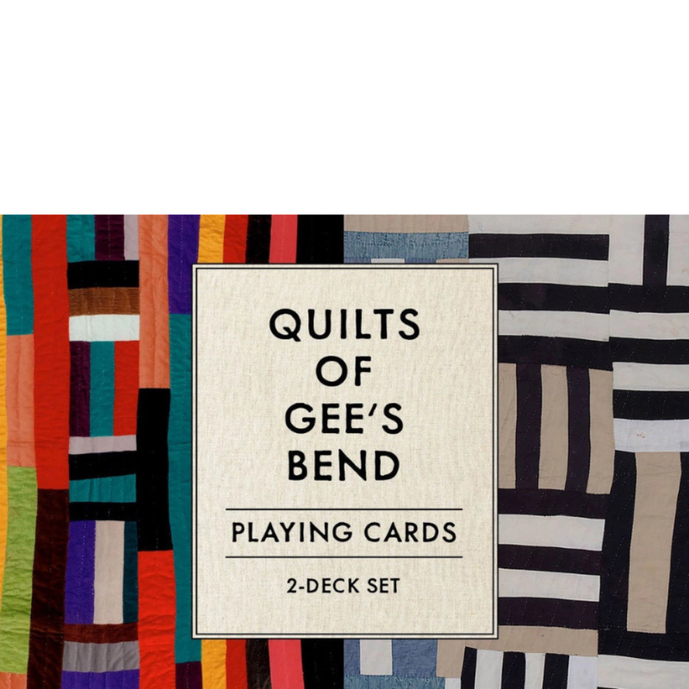Front cover of the 'Quilts of Gee's Bend' playing cards 2-deck set, featuring a central cream-colored textured label with black text, set against a background of colorful quilt patterns.