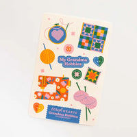 A sticker sheet titled 'My Grandma Hobbies' featuring colorful illustrations of a sewing machine, yarn balls, a cross-stitch hoop, quilt patterns, and heart buttons on an off-white background.