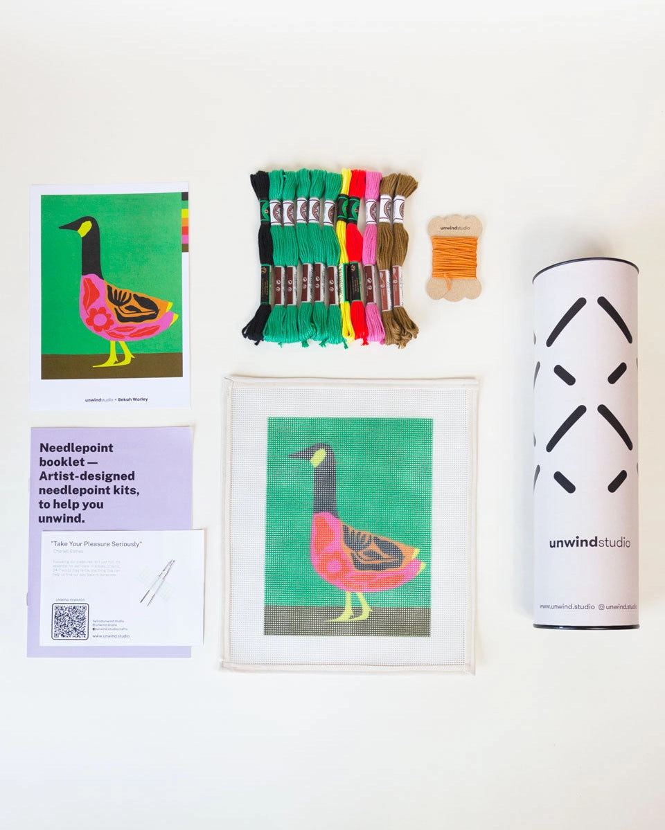 Needlepoint kit materials including a canvas, thread, and instructions on a white background