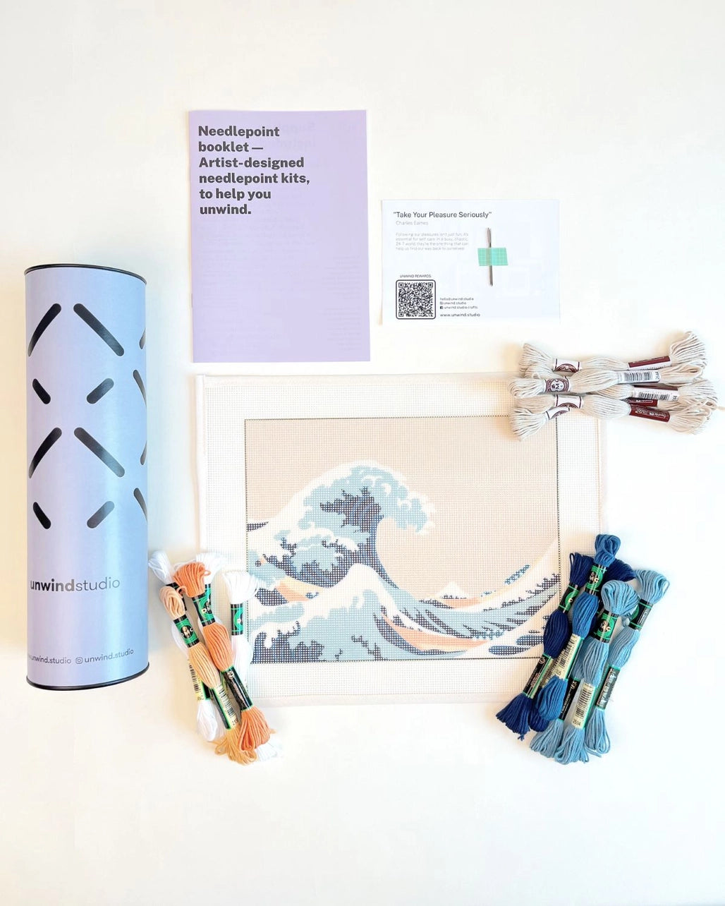 Needlepoint kit materials including canvas, thread, and instructions on a white background.