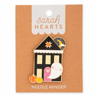 A Halloween-themed Haunted House needle minder pin by Sarah Hearts mounted on its original kraft paper backing card. The pin features a cute haunted house with a smiling ghost, pumpkins, and a crescent moon.