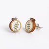 Pair of earrings with embroidery hoops and embroidered leaf designs on a white background