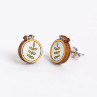 Pair of earrings with embroidery hoops and embroidered leaf designs on a white background