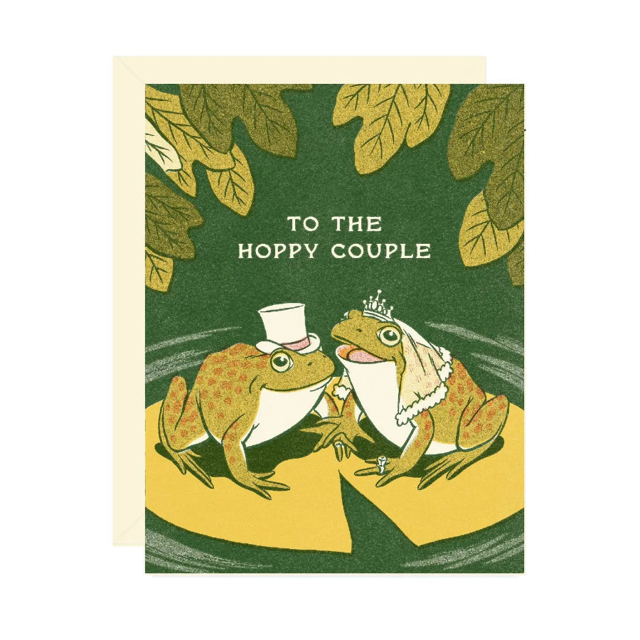 Card with frogs in wedding attire and 'To the Hoppy Couple' text on a green background with leaves.