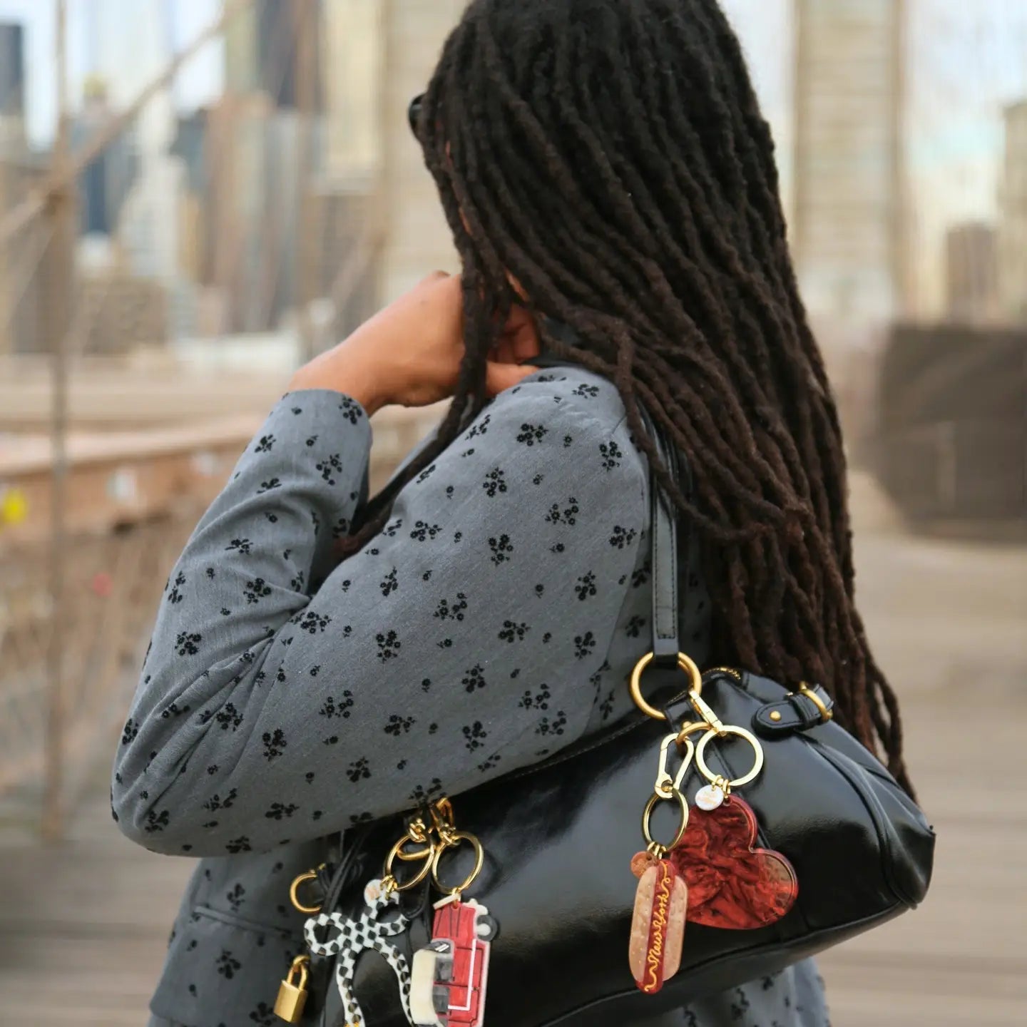 Person holding a black handbag with keychains, blurred background