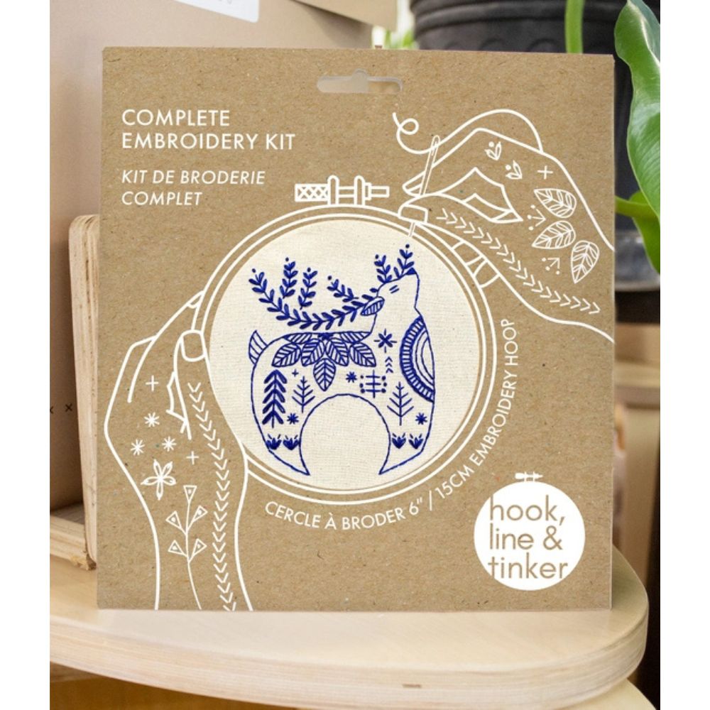 Complete embroidery kit packaging with blue design on brown cardboard