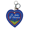 Blue embroidered heart that reads "in spire of ourselves," attached to a silver key ring.