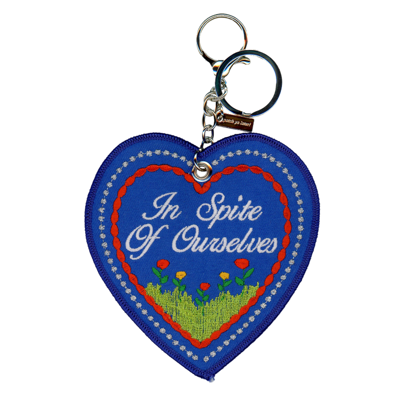 Blue embroidered heart that reads "in spire of ourselves," attached to a silver key ring.