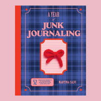 A book titled 'A Year of Junk Journaling' by Martina Calvi, featuring a blue plaid cover with pink lettering and a red yarn bow illustration, set against a solid pink background.
