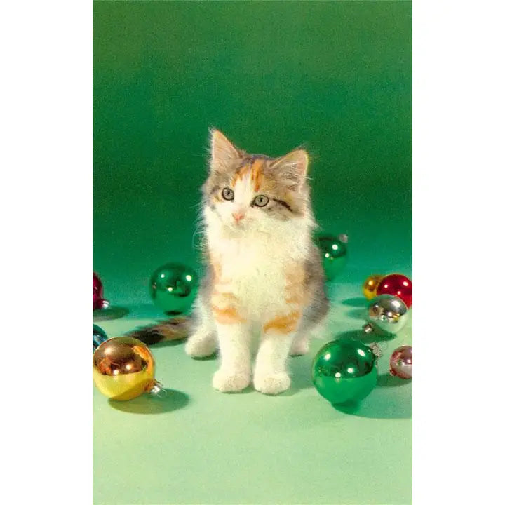 Kitten surrounded by colorful glass balls on a green background