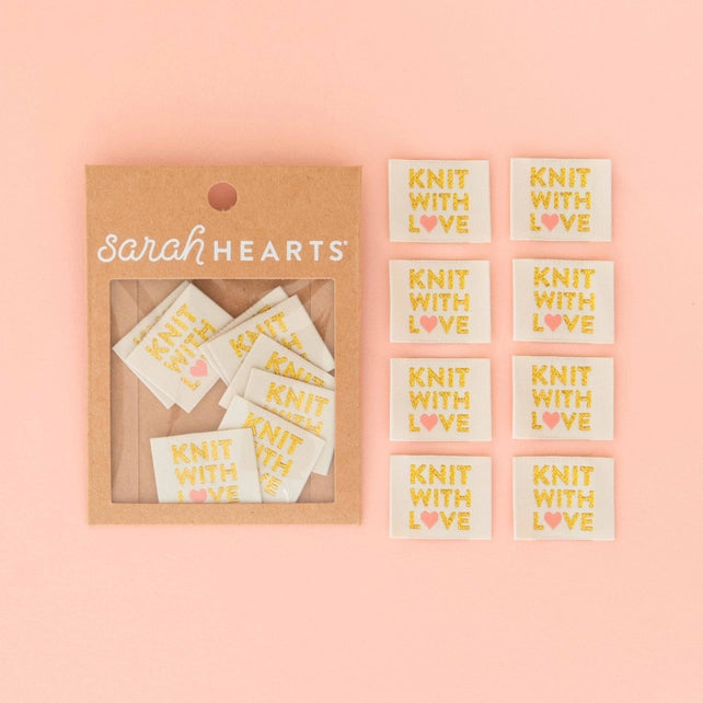 Fabric labels with the text "KNIT WITH LOVE" on a pink background.