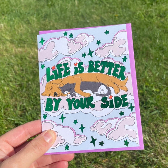 Blue card with cat and dog spooning. 'Life is Better by Your Side' in green lettering