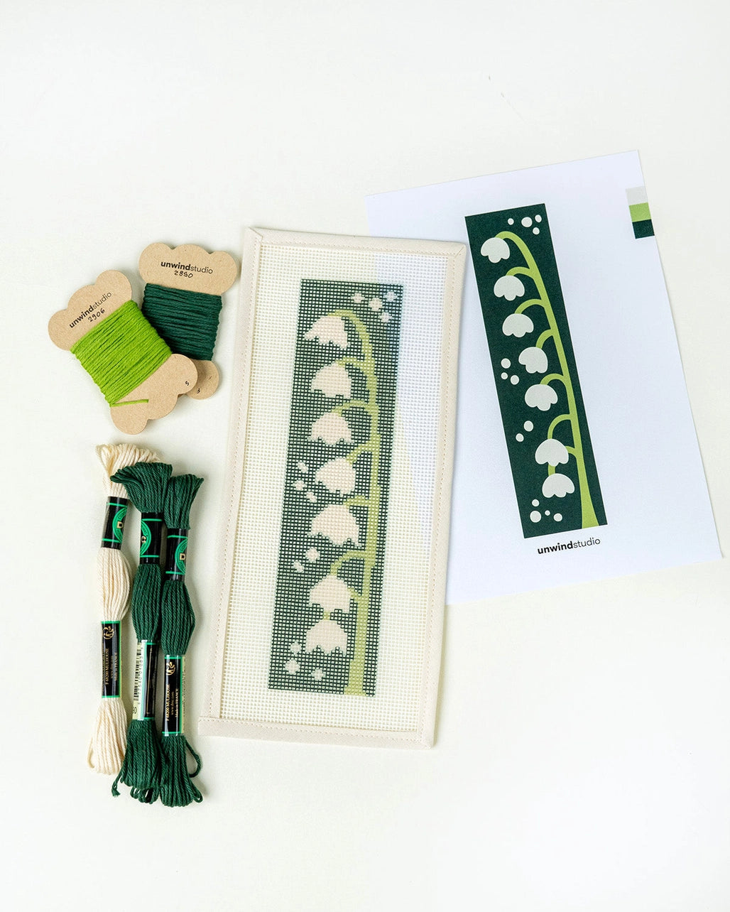 Needlepoint kit with green thread, canvas, and pattern on a white background