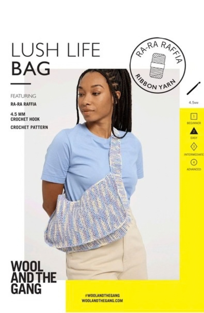 Model in blue tshirt and beige pants holding a multicolored messenger style bag on a white and yellow background with Wool and the Gang branding and text.