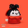 Crocheted character with red sweater and black hair on an orange background, featuring Beetlejuice branding.