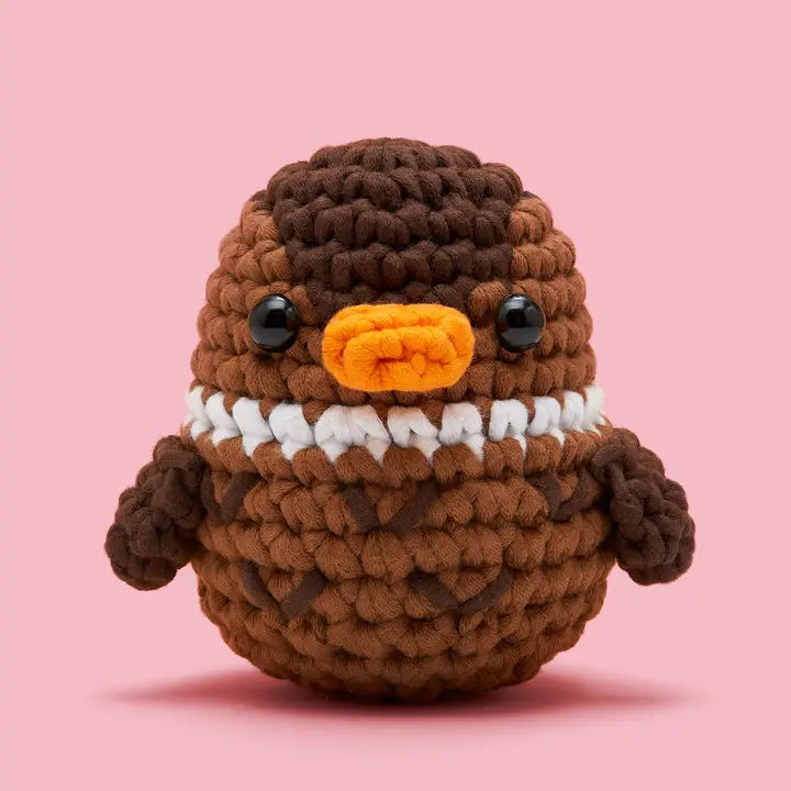 Crocheted duck in shades of brown on a pink background