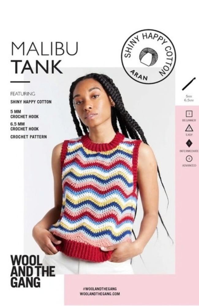 Model in white pants wearing a multicolored zig zag tank top on a white and pink background with Wool and the Gang branding and text.
