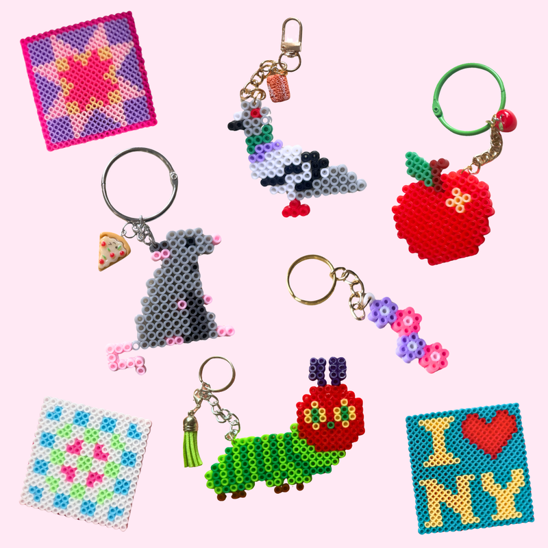 A collection of colorful handmade bead keychains and small bead art pieces arranged on a light pink background. The designs include a rat with a pizza slice charm, a pigeon, a red apple, a green caterpillar, a pink and purple quilt block star, an "I heart NY" pattern, and a white, blue, green, and pink granny square pattern.