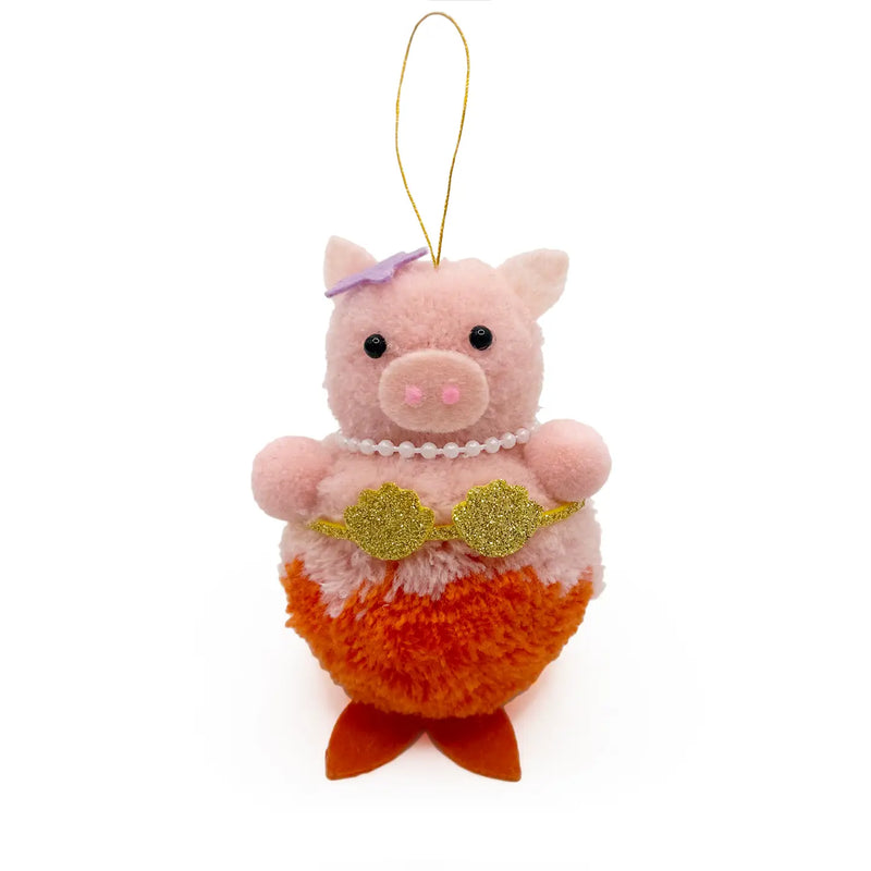 Pink mermaid pig with orange tail and gold seashell bra pom pom ornament on white background.