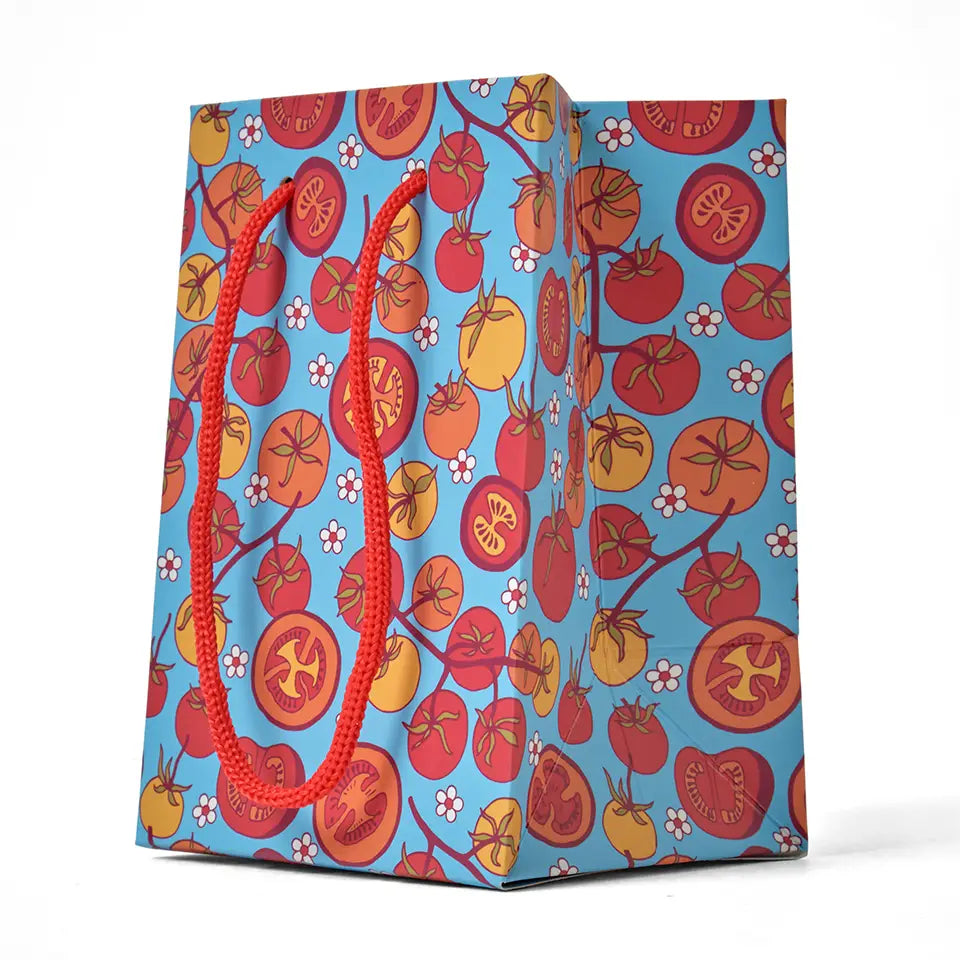 Blue gift bag with tomato design on a white background.