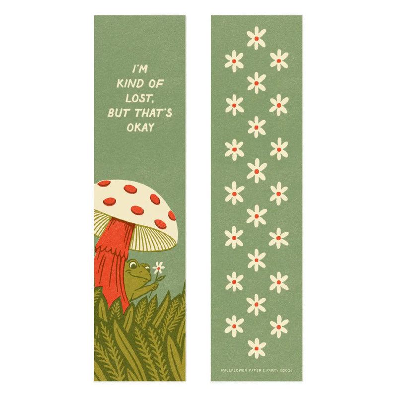 Images of the front and back of a green bookmark featuring a red and white mushroom with a green frog holding a flower beneath it, as well as white flowers on the other side.