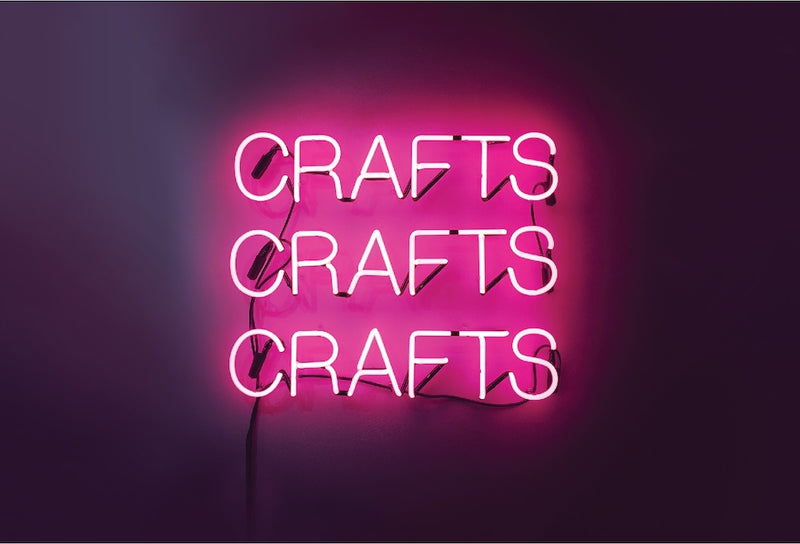 Pink neon sign that reads, "CRAFTS CRAFTS CRAFTS" with a pink glow on a dark purple background.
