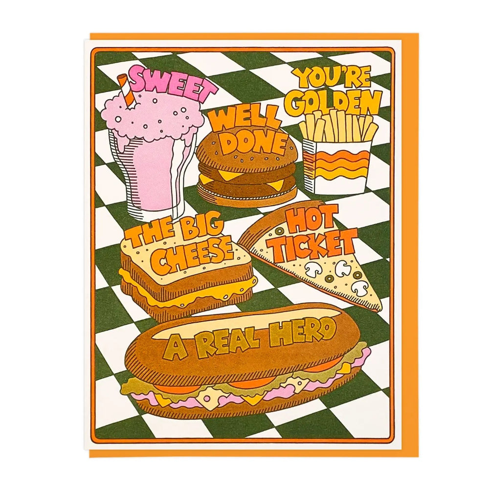 A retro-style illustrated greeting card featuring fast-food items on a green-and-white checkered table. The card includes a pink milkshake with the text 'SWEET', a burger with 'WELL DONE', fries with 'YOU'RE GOLDEN', a cheese sandwich with 'THE BIG CHEESE!', a slice of pizza with 'HOT TICKET', and a long hero sandwich with 'A REAL HERO'.