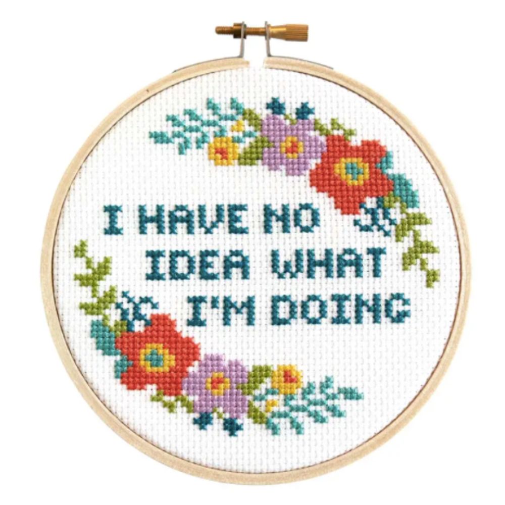 Cross-stitched hoop with colorful flowers and text 'I HAVE NO IDEA WHAT I'M DOING' on a white background