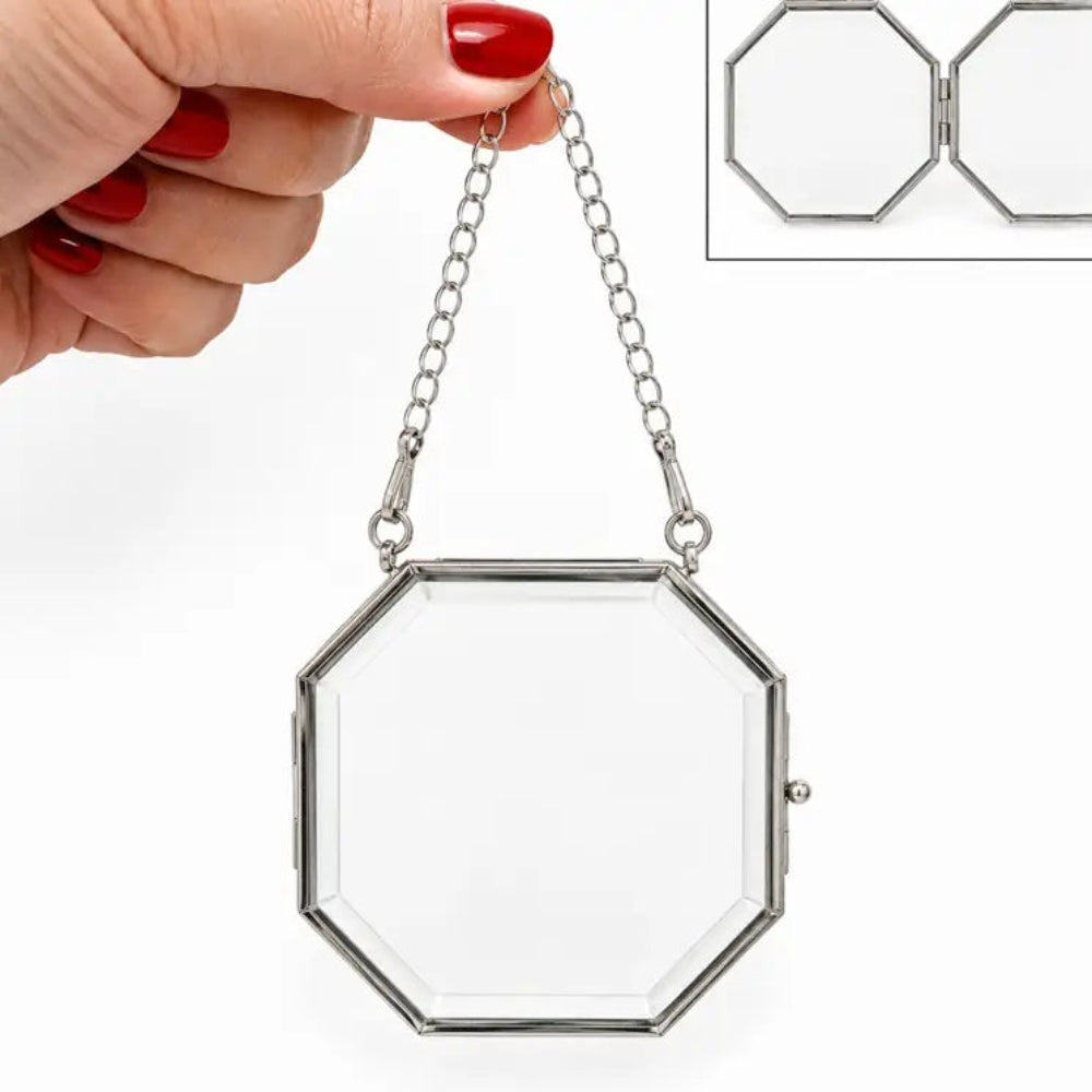 An octagonal silver metal frame and hanging chain, held by a hand with red nail polish. An inset in the top right shows the frame folded open.